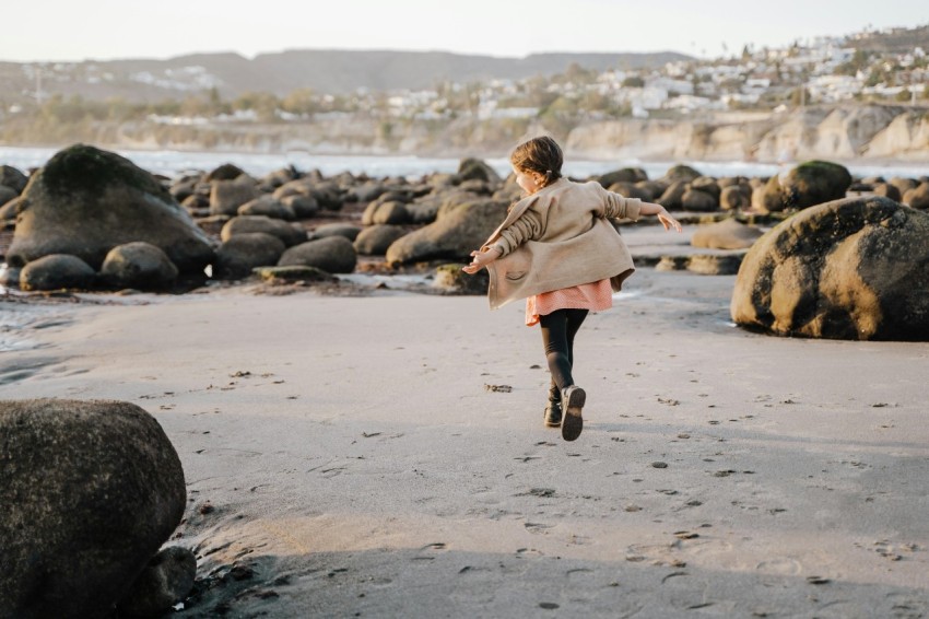 a woman running on a beach with rocks in the background y1euR