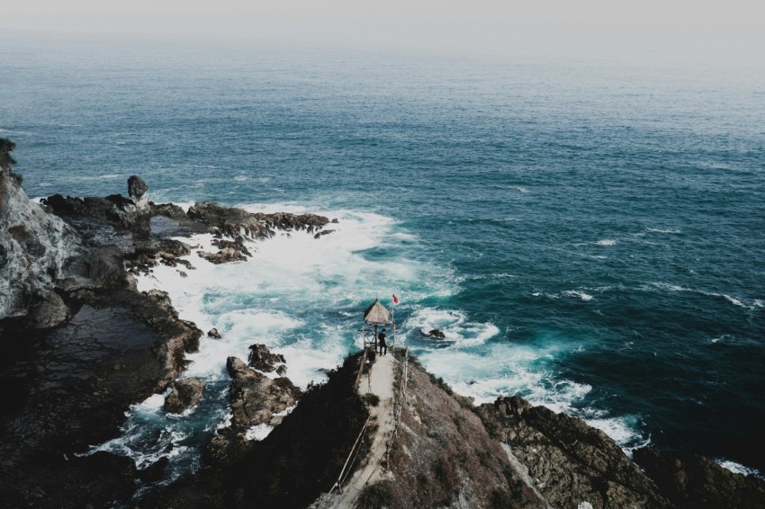 person standing on cliff facing green sea Ueb6