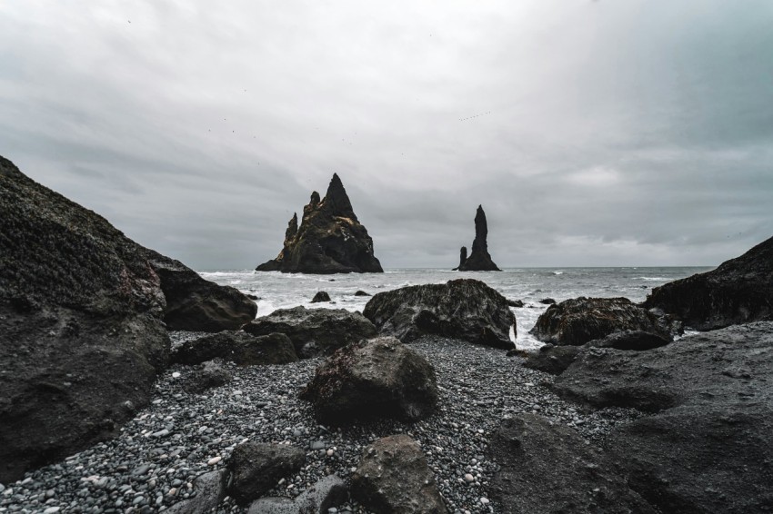 a rocky beach with a rock formation in the background