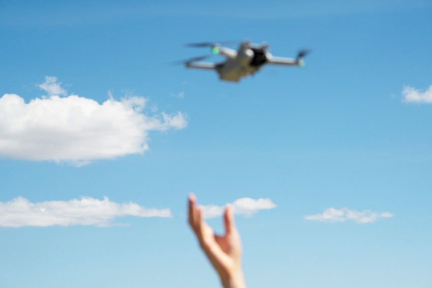 a persons hand reaching up towards a flying object