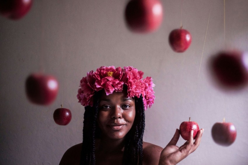 selective focus photography of woman wearing flower headband holding apple fruit