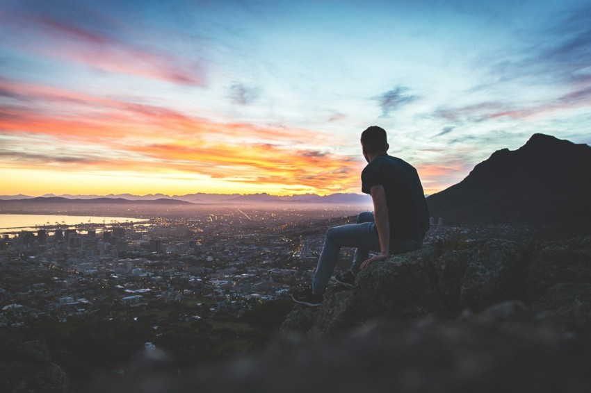 man sitting on rock in front of sea 6V19Uy