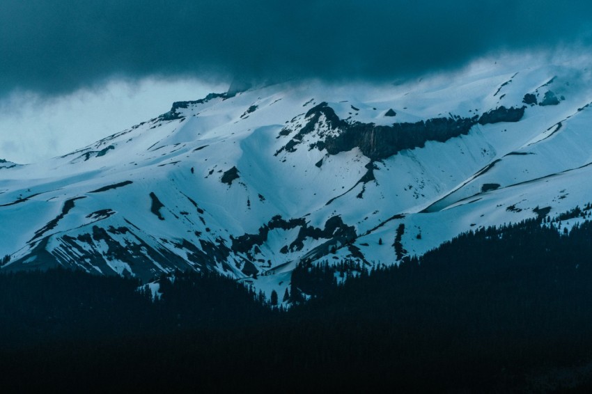 a mountain covered in snow under a cloudy sky