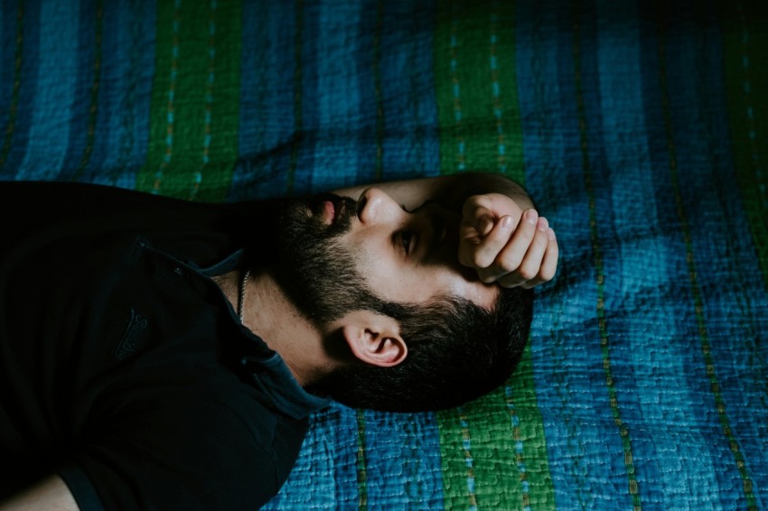 man in black shirt lying on green textile