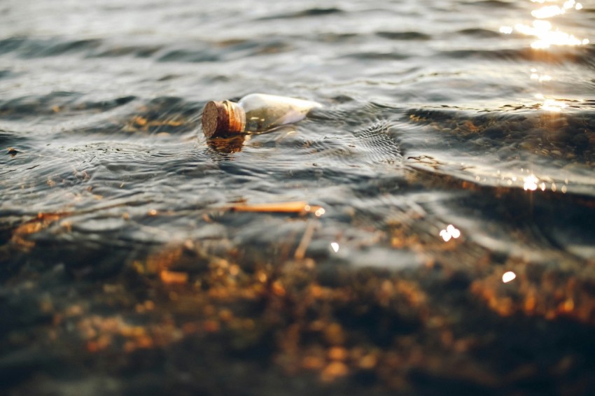 clear glass vial on body of water