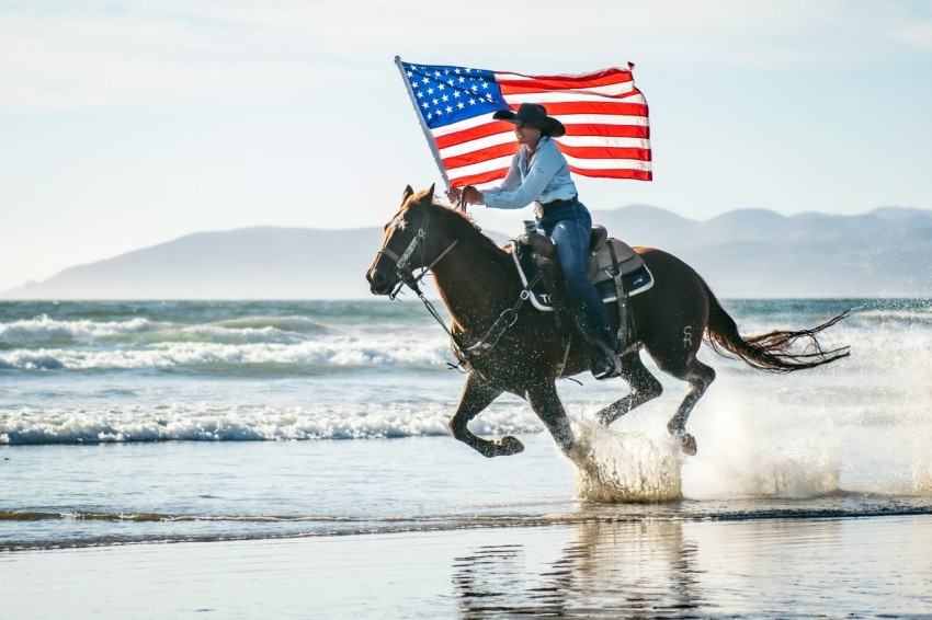 a woman riding a horse with an american flag on its back s