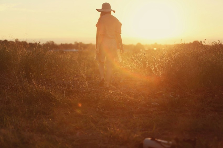 person standing on green grass during sunset