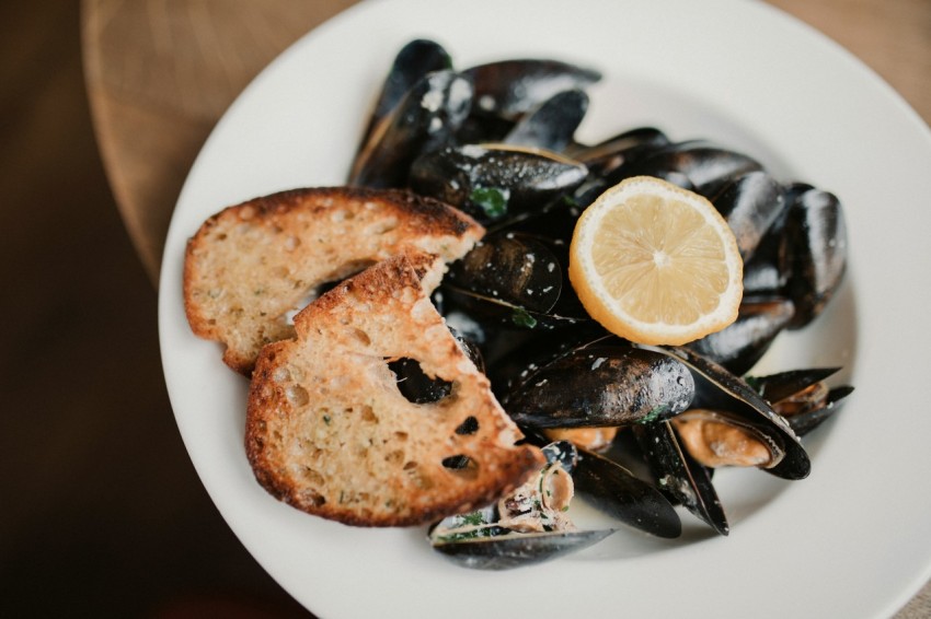 a white plate topped with mussels and a slice of lemon