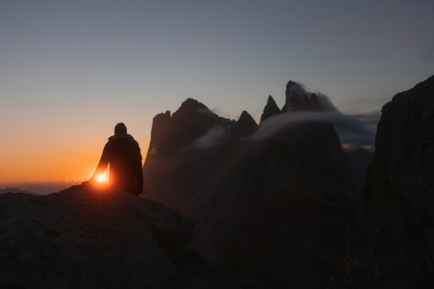 a group of people sitting on a rock looking at the sunset