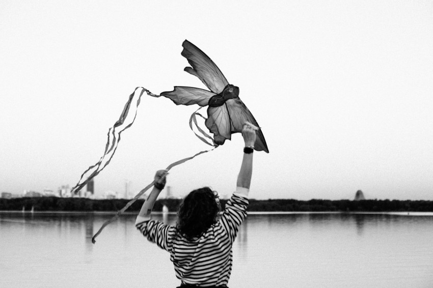 a woman is flying a kite on the beach