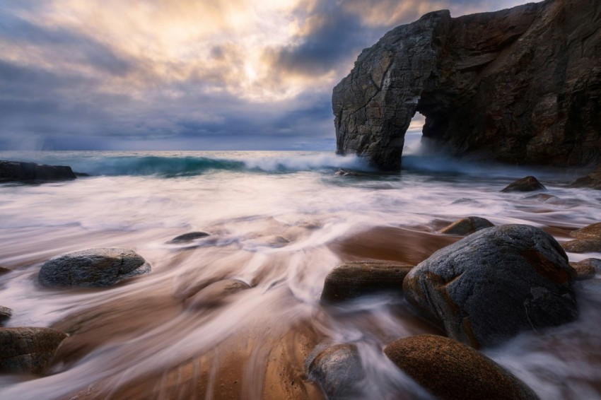 rocky mountain by the sea under white clouds and blue sky during daytime