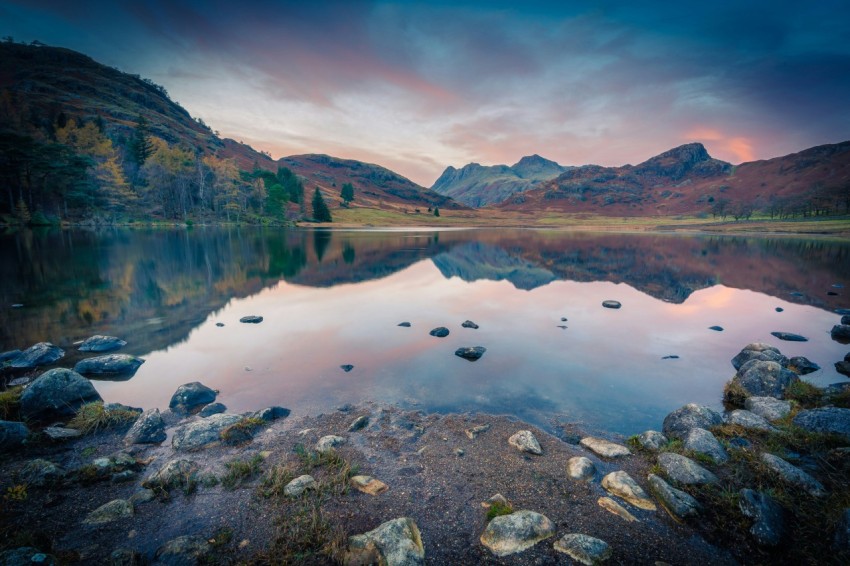 a body of water with rocks and mountains in the background