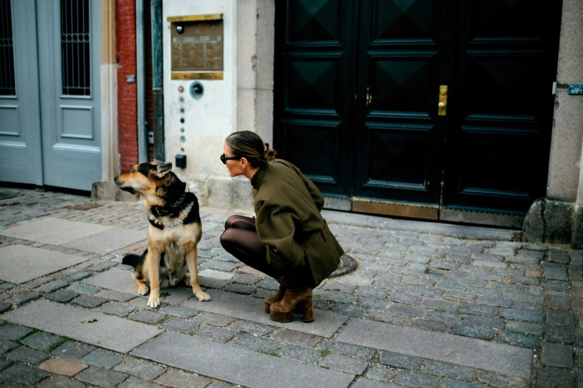 a woman kneeling down next to a dog TB8LXHZeK