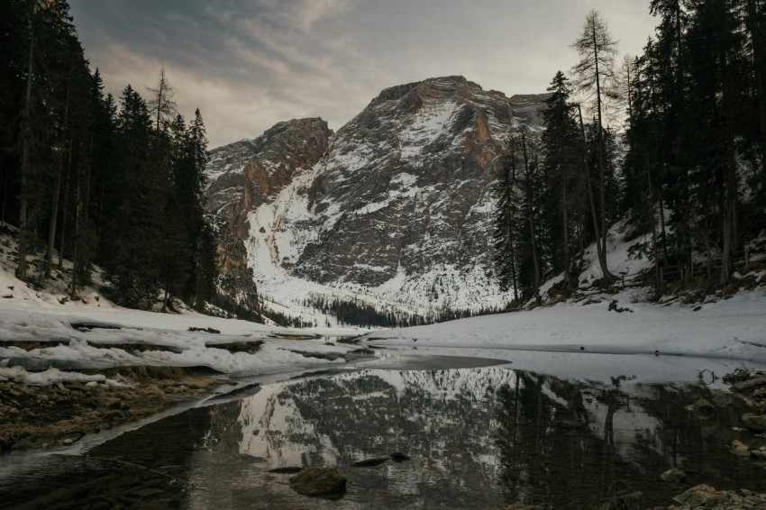 a snow covered mountain with a lake in the foreground