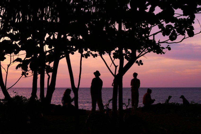 a group of people standing on top of a beach next to the ocean 4wpJ7Gg