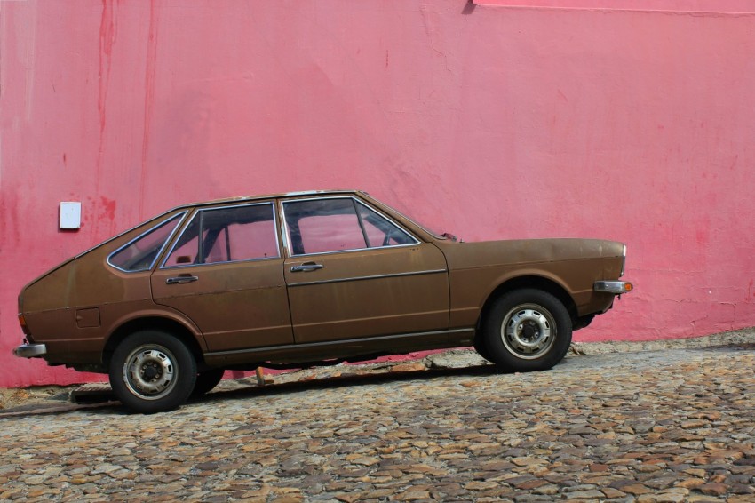 brown 5 door hatchback park beside red wall XV