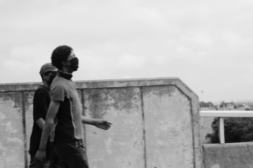 man in black t shirt and black pants standing beside concrete wall during daytime