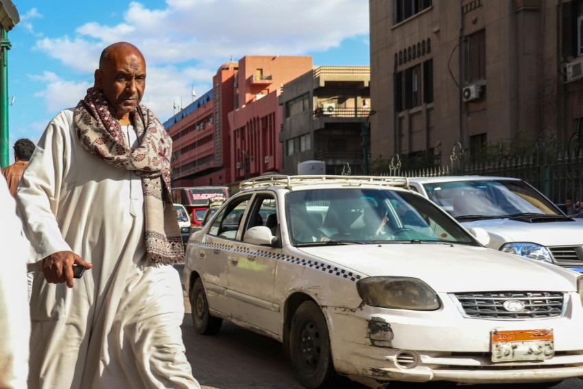 a man walking down a street next to a taxi b1qHIe