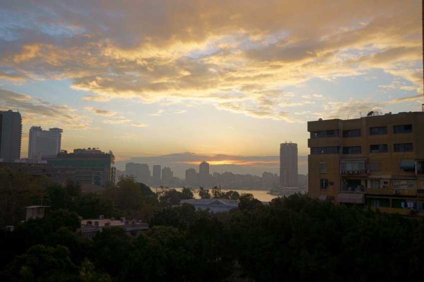 the sun is setting over a city with tall buildings