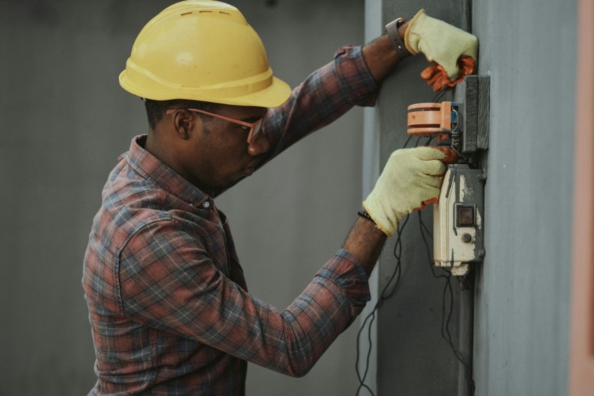 man in brown and white plaid dress shirt and yellow hard hat holding black and orange  0