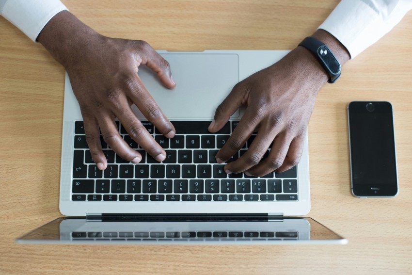 persons hand on macbook near iphone flat lay photography