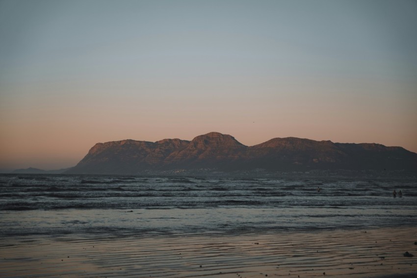 a beach with a body of water and mountains in the background