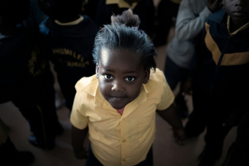 boy in yellow dress shirt surrounded by people pbM