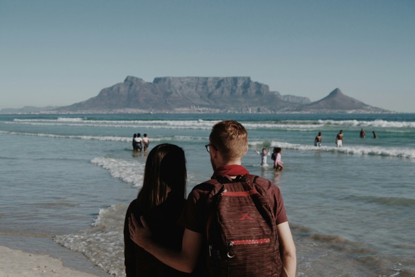 man in red and black backpack sitting on beach during daytime