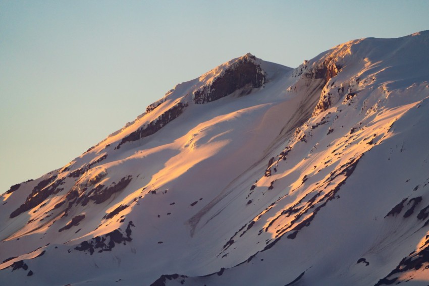 a large mountain covered in snow under a blue sky