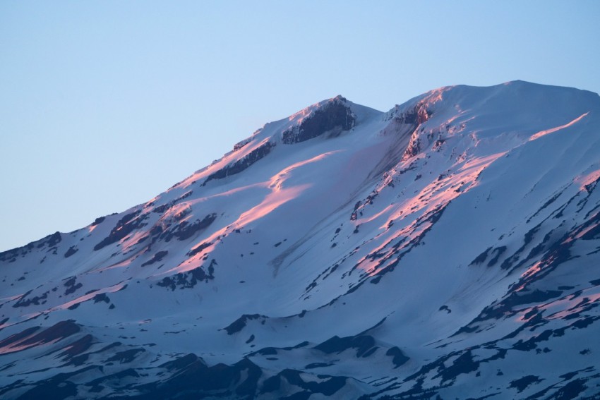 a large mountain covered in snow under a blue sky