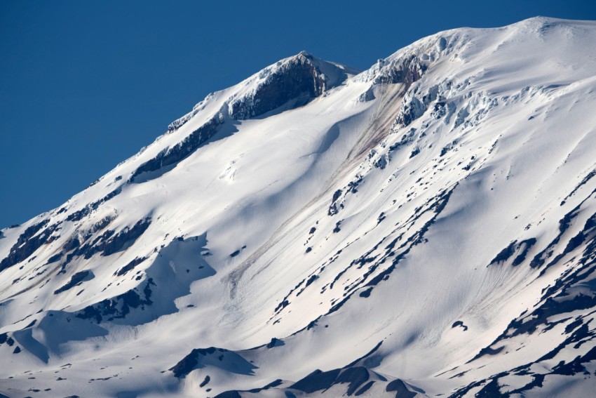 a large mountain covered in snow under a blue sky jUeq