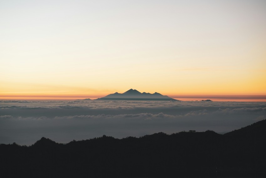 a view of a mountain in the distance above the clouds