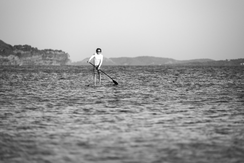 greyscale photo of man man on surfboard during daytime