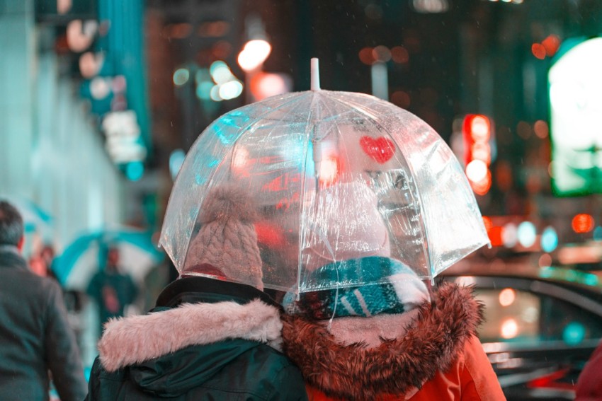 two person wearing coat holding white umbrella