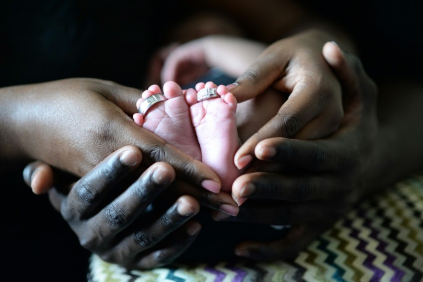 person touching babys feet with two silver colored rings