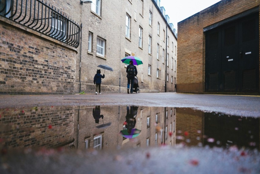 person in black jacket holding umbrella walking on sidewalk during daytime