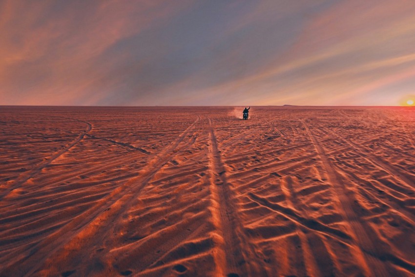 person riding motorcycle on sand field at daytime