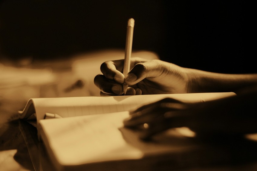 a person holding a pen and writing on a piece of paper