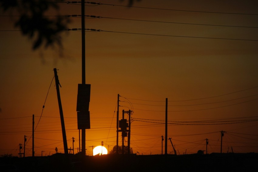 the sun is setting behind power lines and telephone poles