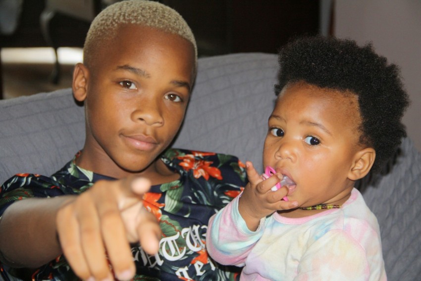 two young children sitting on a couch brushing their teeth