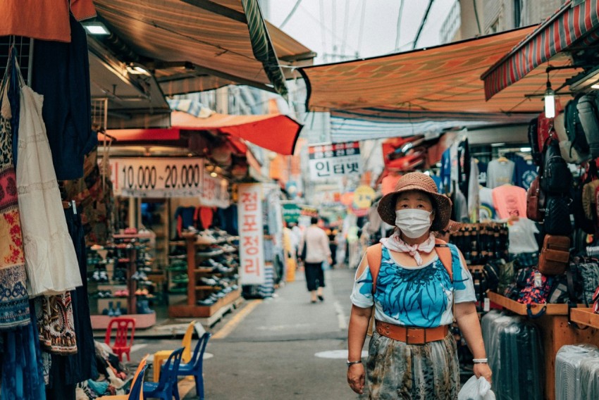 woman in blue and white floral dress wearing red hat standing on sidewalk during daytime