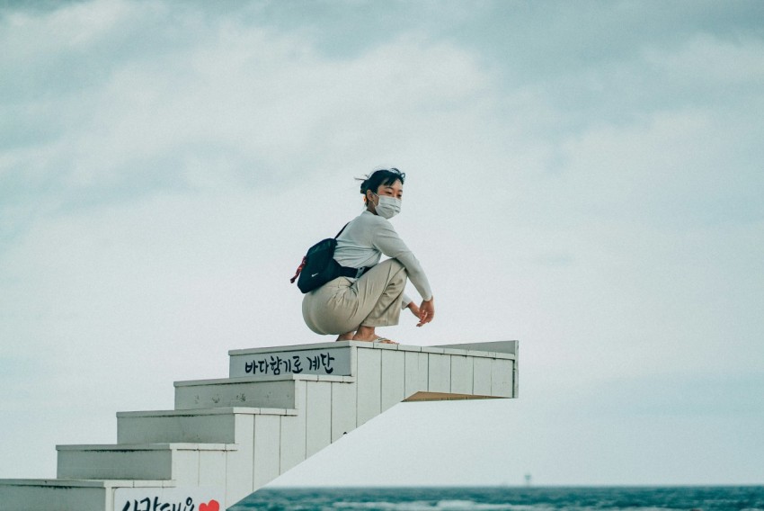 man in white long sleeve shirt and black pants sitting on white concrete wall during daytime