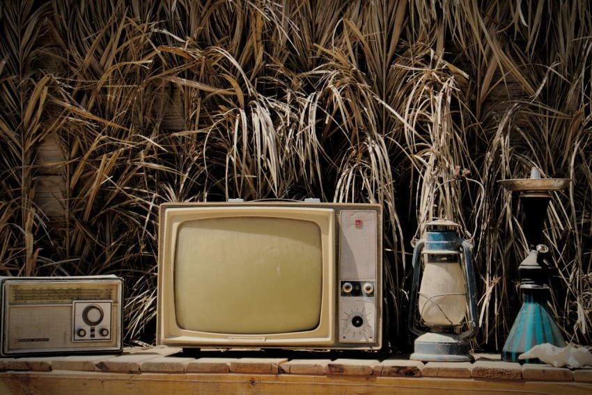 an old tv sitting on top of a wooden shelf