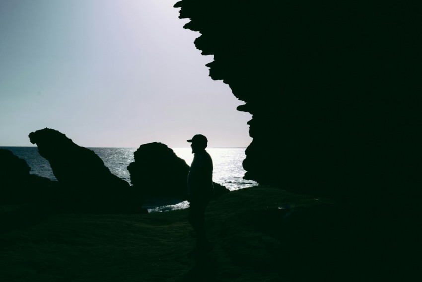 a silhouette of a man standing next to the ocean