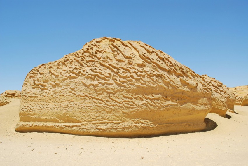 a large rock sitting in the middle of a desert