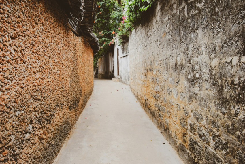 gray concrete pathway between brown brick wall