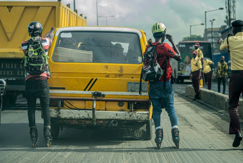 man in red jacket and blue denim jeans standing beside yellow car during daytime