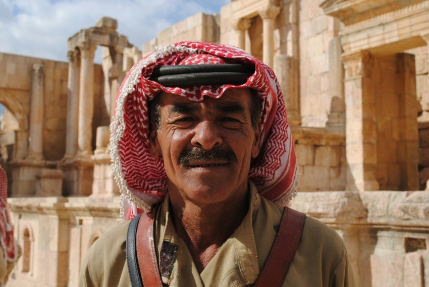 close up photo of man wearing keffiyeh behind concrete building