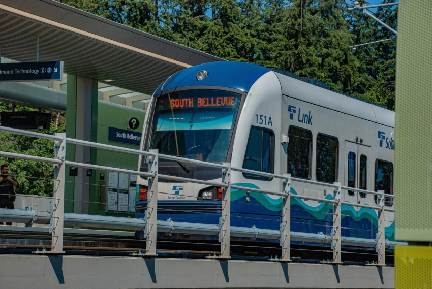 a blue and white train traveling past a train station