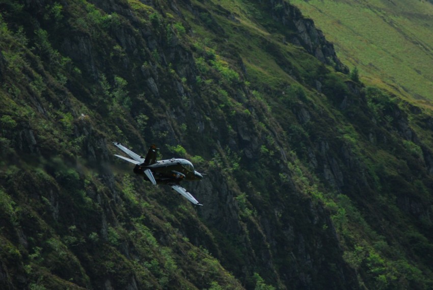 black airliner in flight above green mountains tkY29p